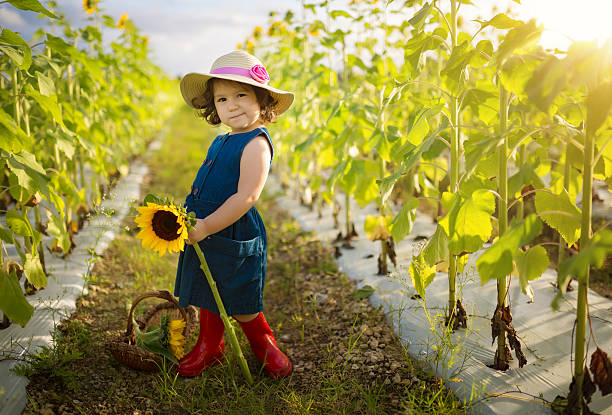 Little serious girl in a wreath of yellow leaves stands on the lawn. High quality photo