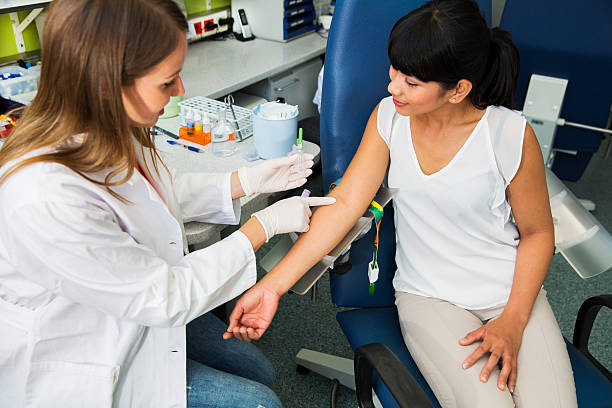 Drawing blood...young doctor prepairing for blood capture Drawing blood...young doctor prepairing for blood capture from a vein for laboratory analyses from cute young woman blood bank stock pictures, royalty-free photos & images