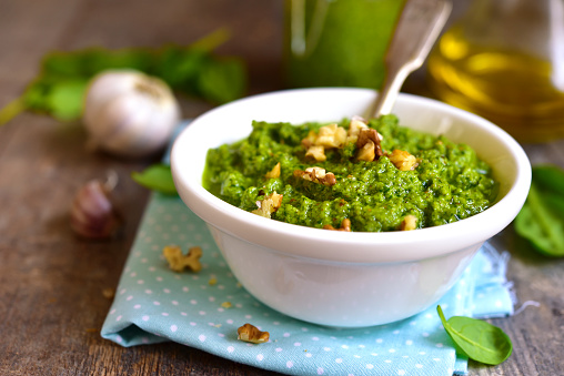 Homemade spinach pesto with walnut in a white bowl.