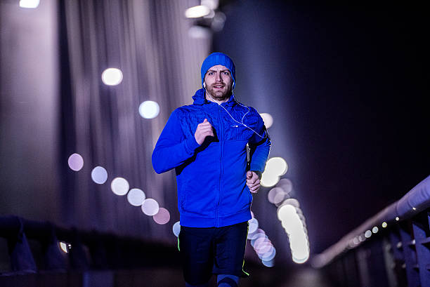 Young man jogging through the city at night