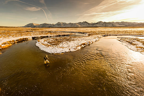 Aerial View Of Flyfisherman In the River At Sunset An Aerial View Of Fly fisherman In the River At Sunset.  Warm tone added to the image for a romantic mood. owens river stock pictures, royalty-free photos & images