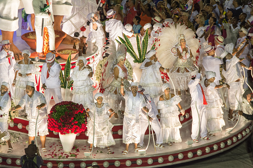 Rio de Janeiro, Brazil - February 08, 2016: Group of people dressed in white dancing on the top of a Candomblé/ Umbanda/ Macumba-themed carnival float.