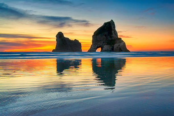 Sunset at Wharariki beach, New Zealand Sunset at Wharariki beach, West coast, South Island, New Zealand. tasman sea stock pictures, royalty-free photos & images