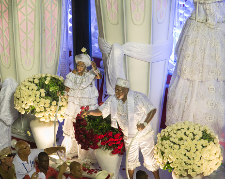 Rio de Janeiro, Brazil - February 08, 2016: Man and woman dressed in white giving flowers away from the top of a Candomblé/ Umbanda/ Macumba-themed carnival float.