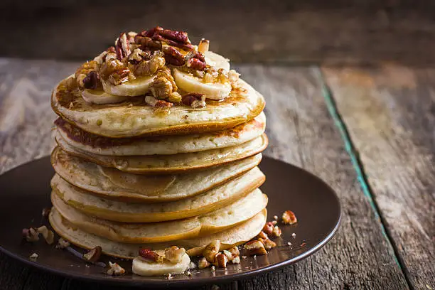 pancakes with banana, nuts and honey on wooden background