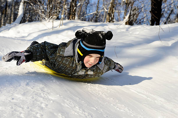 маленький мальчик езда с холмами в санки - little boys sled clothing slide стоковые фото и изображения