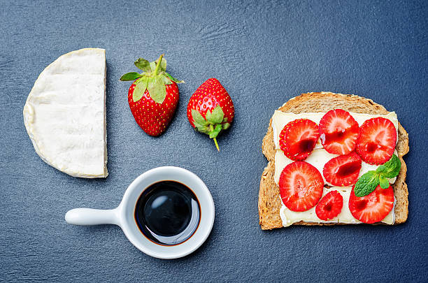 Sandwich with cheese, strawberries and balsamic vinegar on a black background. toning. selective focus