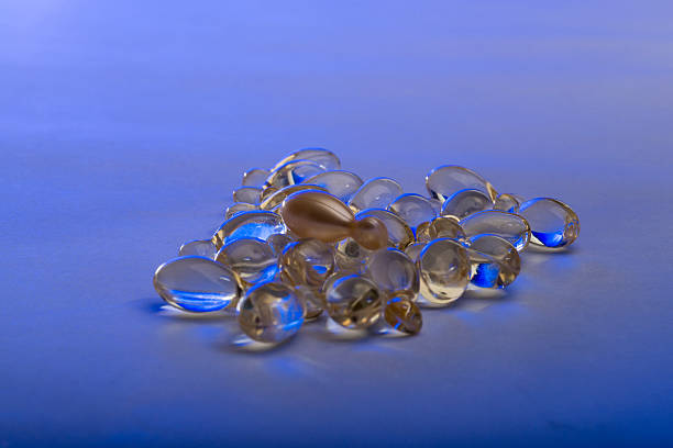 gel cápsulas sobre el fondo blanco iluminado con iluminación azul - spa treatment capsule body care hair gel fotografías e imágenes de stock