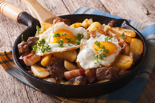 Tyrolean fried potatoes with meat, bacon and eggs in pan