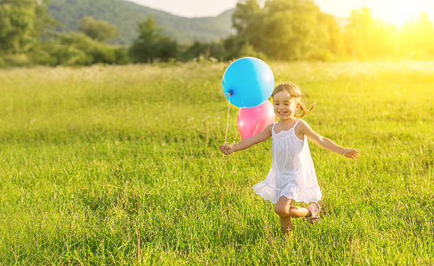 счастливый веселая девочка играет и весело на воздушных шарах - baby spring child grass стоковые фото и изображения