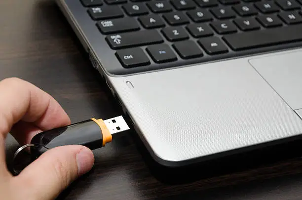 Photo of Hand inserting USB flash drive into laptop computer port close-up