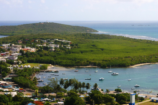 A view of Las Croabas Fishing Village and Las Cabezas de San Juan Lighthouse.  The second oldest lighthouse in Puerto Rico. Located at Fajardo, Puerto Rico (Caribbean).  Several fishermen boats in the bay.  Blue sea and sky.