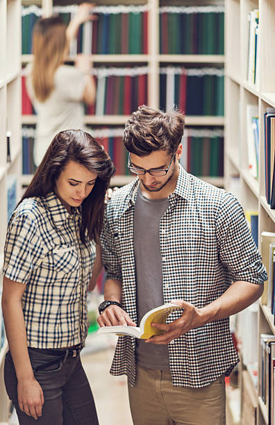 istock Young couple reading a book in a library. 509227642