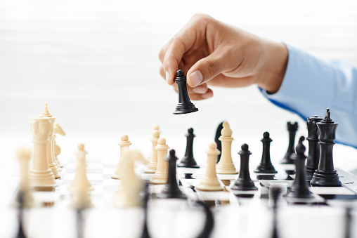 Hand of businessman playing chess: strategy and tactics in business