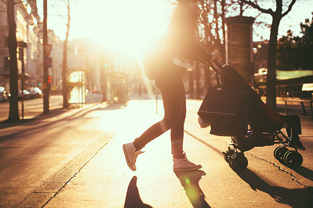 Urban mom with strollers Photo of a modern mom having an easy walk and shopping with her baby in the strollers, outdoors in the city baby stroller stock pictures, royalty-free photos & images