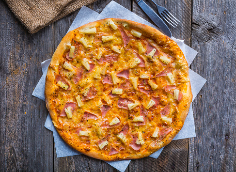 Hawaiian Pizza on a old wooden table