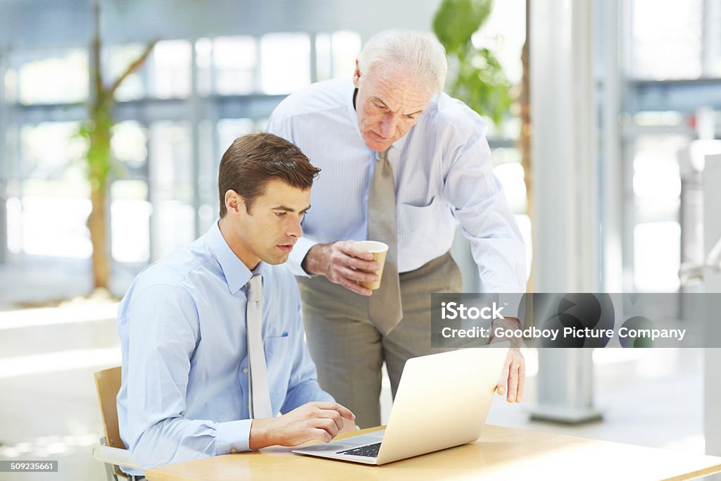 His laptop is an important business tool Cropped shot of two businessmen discussing information on a laptop Active Seniors Stock Photo