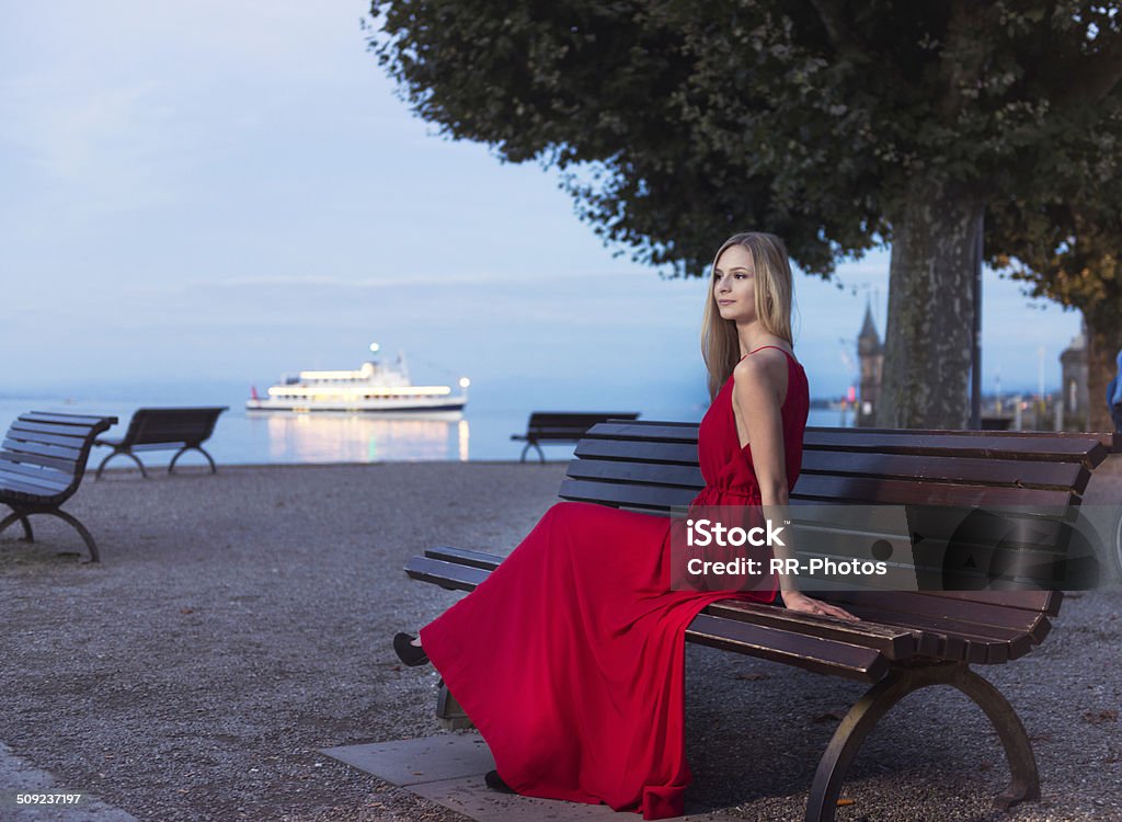 젊은 너무해 여자 앉아 해질녘까지 on the promenade constance - 로열티 프리 Red Dress 스톡 사진