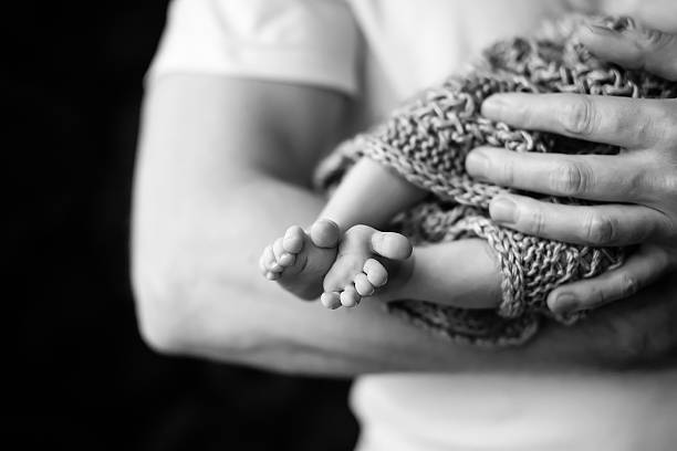 детские ножки в отец руки. черно-белые фото. - human foot baby black and white newborn стоковые фото и изображения