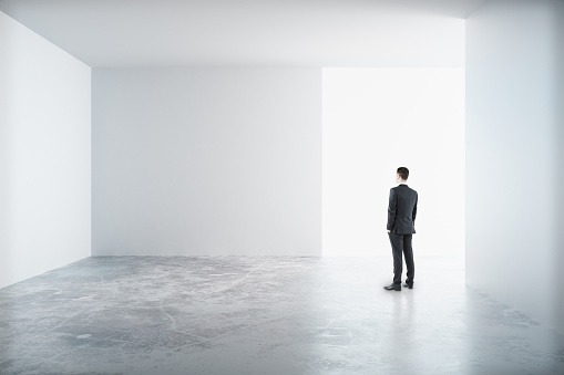 Man standing in a white room and looking to the blank wall, mock up