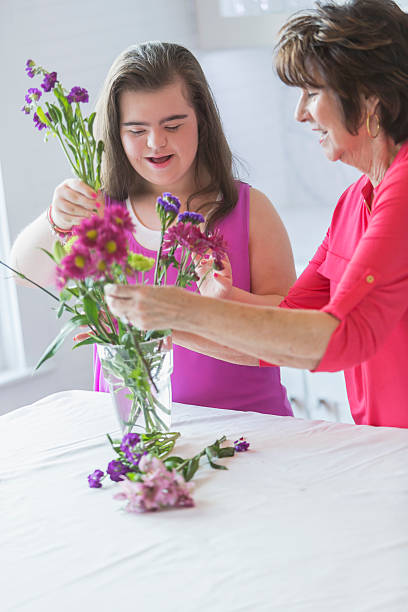 fille avec trisomique, grand-mère arranger des bouquets de fleurs - vertical single flower women teenager photos et images de collection