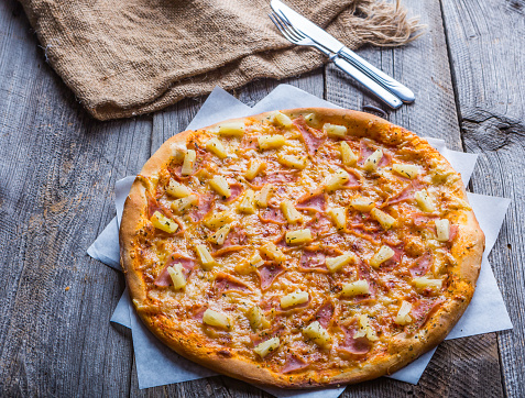 Hawaiian Pizza on a old wooden table