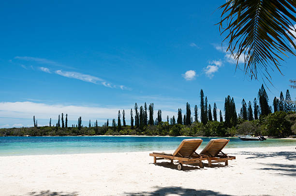 Kanumera beach on the Isle of Pines in New Caledonia Kanumera beach on the Isle of Pines in New Caledonia. There are a pair of beachchairs on the white sand. The bay is surrounded by pacific cedars and is known as one of the most beautiful bays in the world. new caledonia stock pictures, royalty-free photos & images