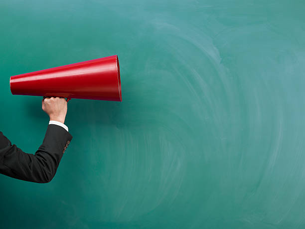 istock Red Megaphone In Human Hand On Green Blank Blackboard 509245326