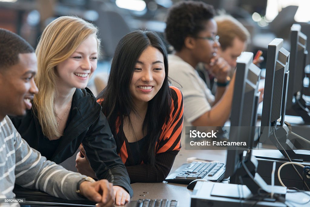 Working in the Computer Lab A multi-ethnic group of college age students are working together on a computer in the computer lab. Classroom Stock Photo