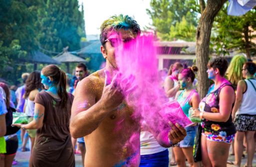 San Antonio, Ibiza, Spain - August 21, 2014: Taken at the Holi Garden Festival in San Antonio, Ibiza.  Hundreds of tourists and holidaymakers make there way to The Holi Garden Festival in Ibiza every week.  Here we can see a few of the party goers throwing coloured paint at each other.  Holi festivals have events all over the world and are becoming more and more popular.  People can buy bags of coloured powder and every hour they have a countdown, as the timer hits zero everyone is supposed to throw their pain in the air in what is called a 