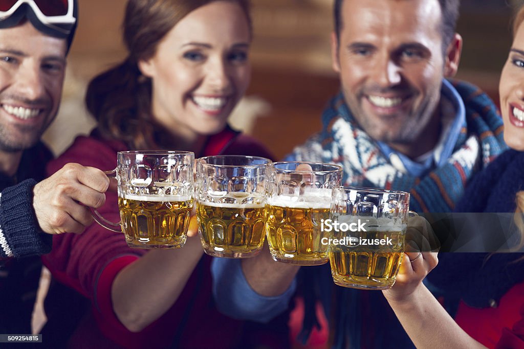 Friends Having Good Times Group of friends wearing warm clothes toasting with beer. Focus on beer glasses. Adult Stock Photo