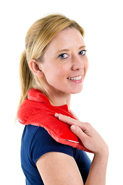 Close Up Portrait of Smiling Blond Woman Relaxing with Red Heat or Cold Pack on Shoulders in Studio with White Background.