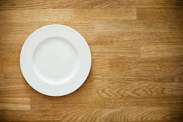 Empty white plate on wooden table. Template for your design.