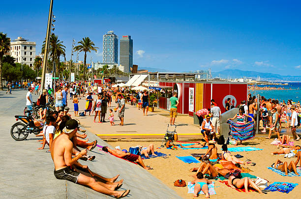 Barcelona, Spain - August 19, 2014:  A crowd of bathers in La Barceloneta Beach  in Barcelona, Spain. This popular beach hosts about 500,000 visitors from everywhere during the summer season