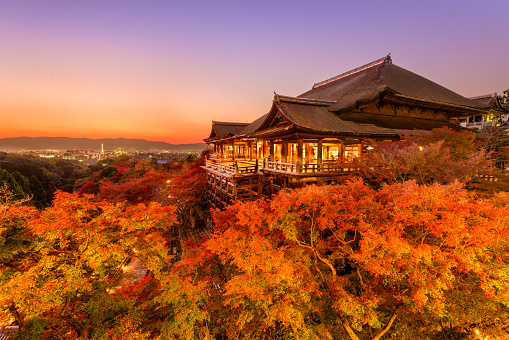 Kyoto, Japan - November 30, 2015: Tourists stand on the stage of Kiyomizudera Temple during the autumn season at dusk. The temple was founded in the 700's and the present stage structure dates from 1633.
