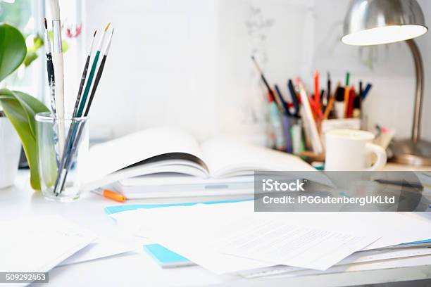 Desk With Books Papers And Brushes Stock Photo - Download Image Now - Book, Business, Cluttered