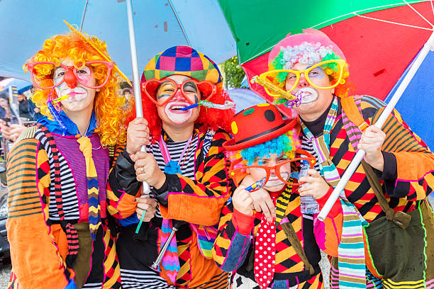 Prado, Portugal - February, 9th 2016: Four people dressed as colourful clowns costumes for the carnaval in Prado, Portugal, holding umbrellas in the drizzling rain.  Prado has its yearly Carnaval display procession through the city centre.