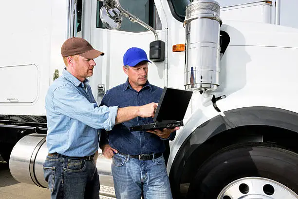A royalty free image from the trucking industry of two truck drivers using a laptop computer.