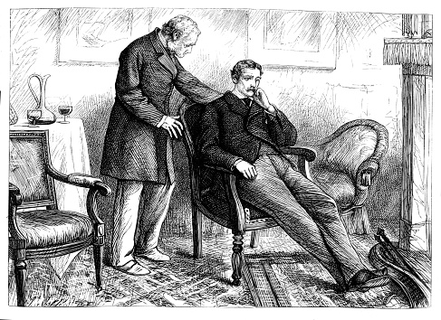 Picture shows a man standing in a livingf room with another man seated on a chair. 