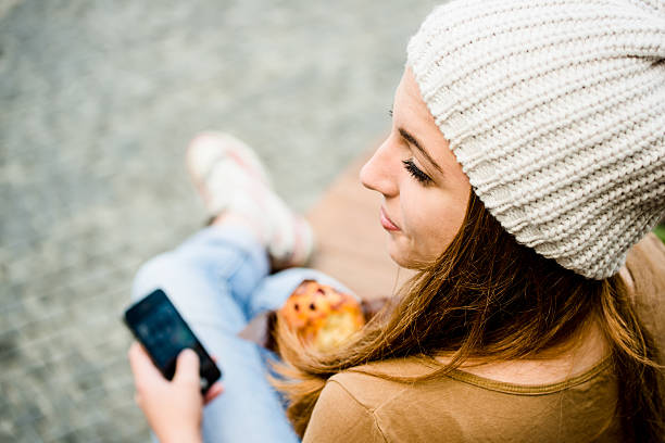 adolescente mangiare muffin alla ricerca del telefono - muffin blueberry muffin blueberry food foto e immagini stock