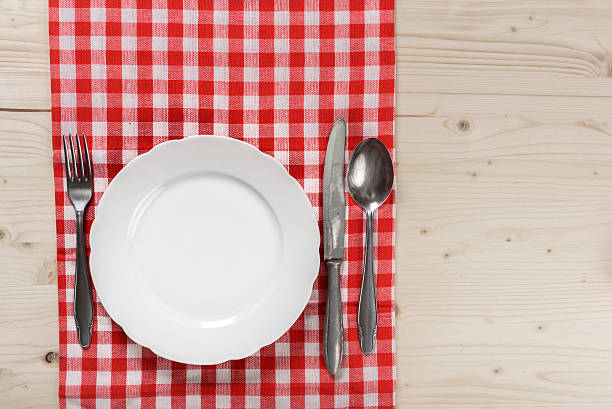 istock Wooden Table with Checkered Red Tablecloth Plate Spoon Knife Fork 509303596