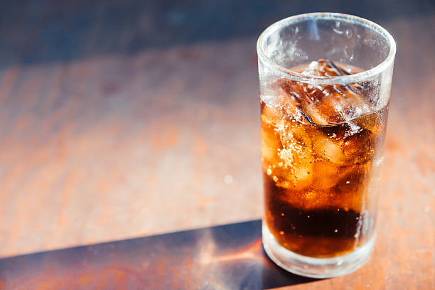 istock Glass of cola with ice on wooden table 509308418