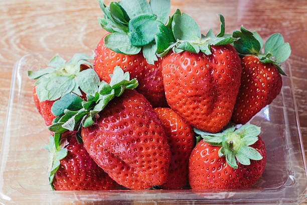 istock ripe strawberries in plastic container on wood table 509308502