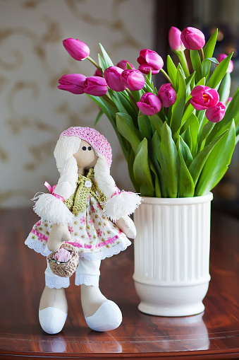 Cute handmade doll and spring bouquet of tulips