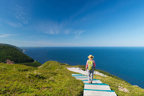 Woman walking, hiking, Skyline, Cabot trail, Cape Breton, Nova Scotia Woman walking on boardwalk at the top of Skyline Trail in Cape Breton Highlands National Park, Cabot Trail in Nova Scotia, Canada. gulf of st lawrence photos stock pictures, royalty-free photos & images