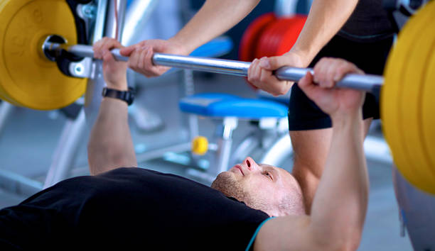 istock Young man lifting the barbell in gym with instructor 509308714