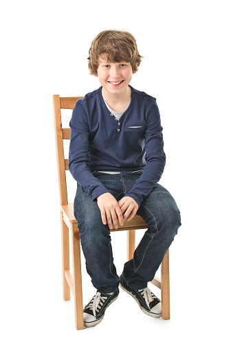 picture of curly 12 years old boy isolated on white. He is sitting. full length