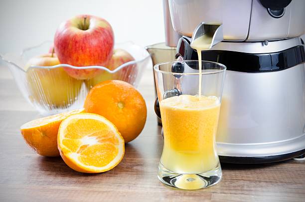 juicer and orange juice. fruits in background - 榨汁機 個照片及圖片檔