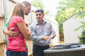 Air Conditioner repairman explaining cost of repairs to homeowners