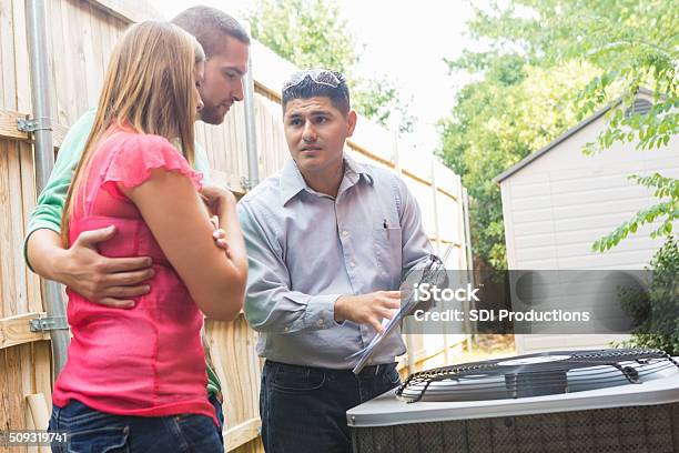 Air Conditioner Repairman Explaining Cost Of Repairs To Homeowners Stock Photo - Download Image Now